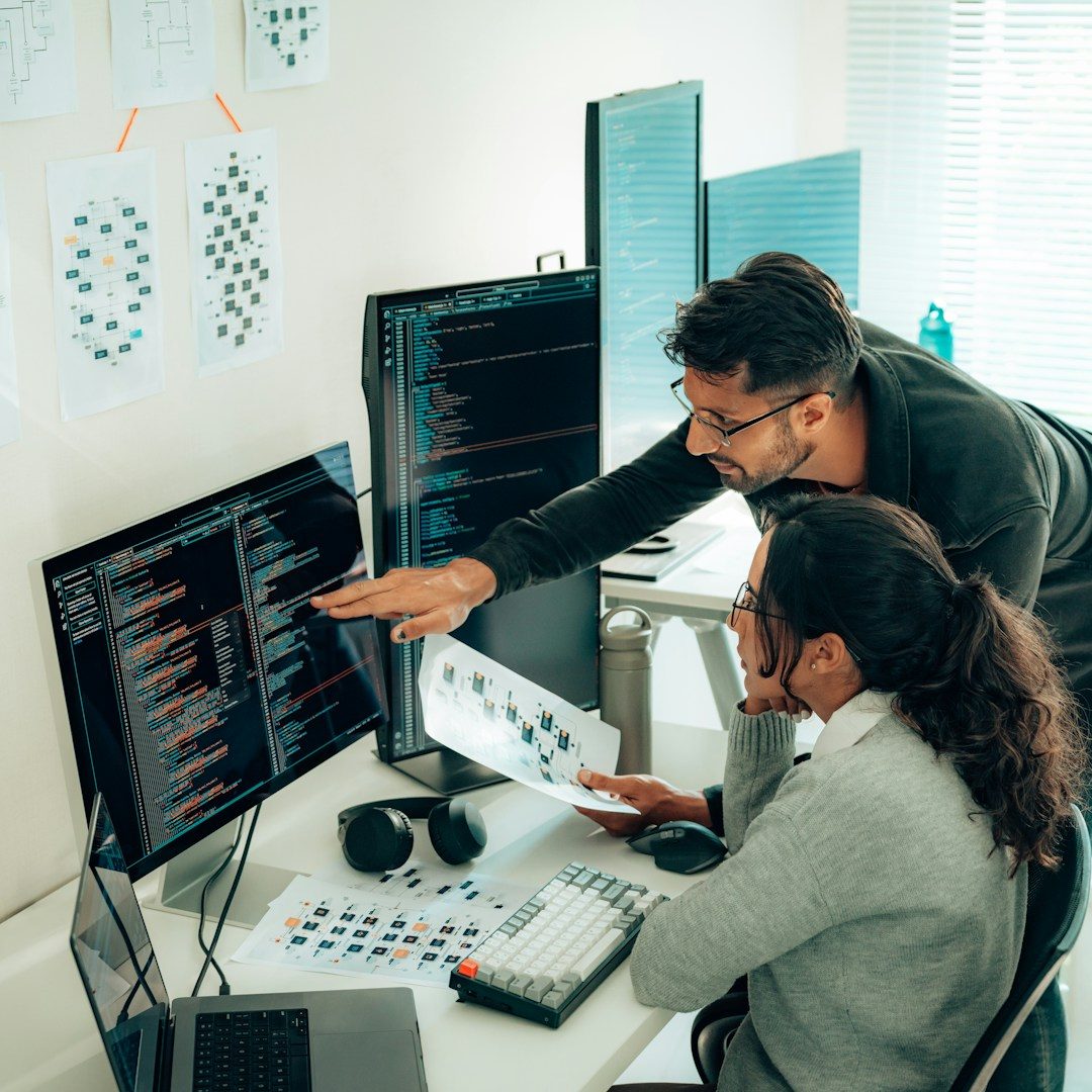 Beratung Zwei Personen arbeiten an mehreren Monitoren, planen und analysieren Daten.